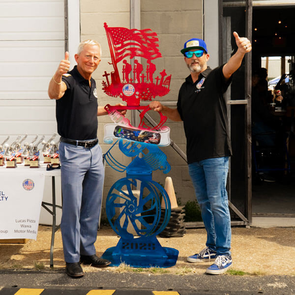 Andre with supporter in front of a custom metalwork sculpture