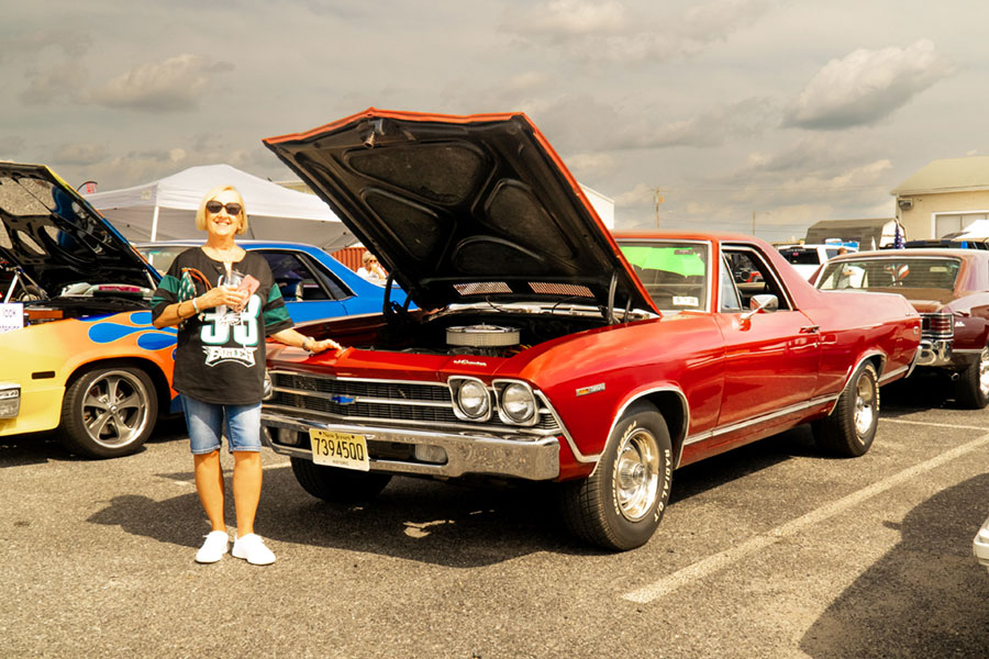 woman next to classic red car at a car show