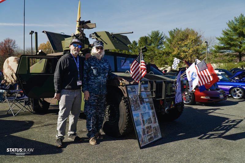 Andre posing with a veteran next to a tank at an event