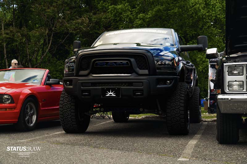Black Ram truck displayed between cars at outdoor show