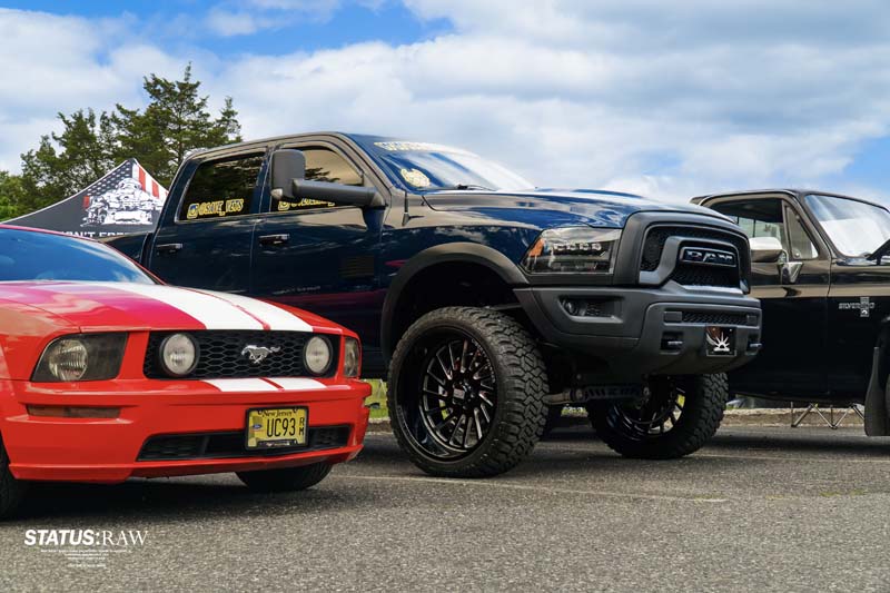 Black Ram truck parked next to red Ford Mustang at car show