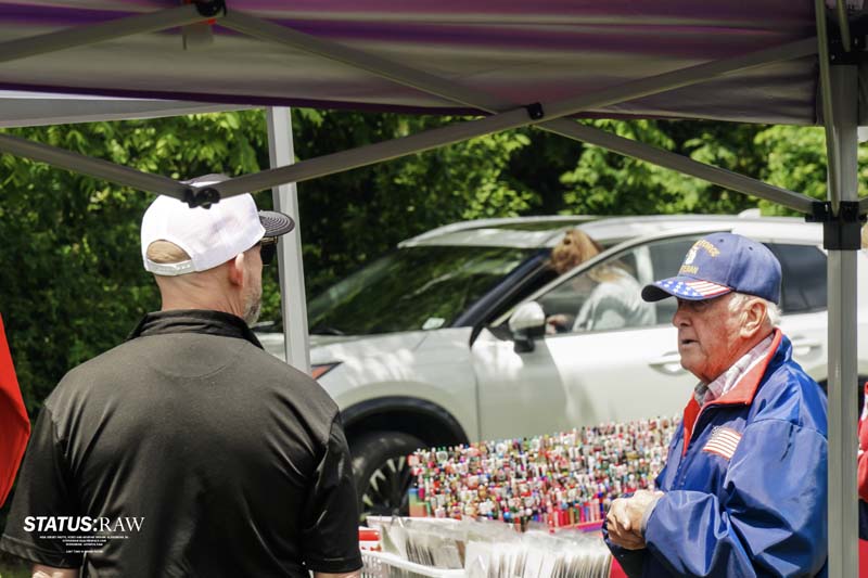Two people talking under tent at table with small items display