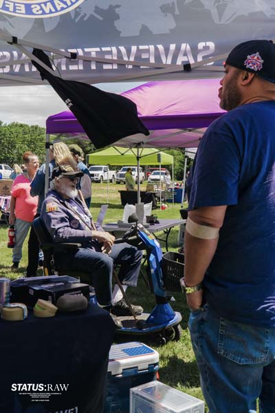 Person on mobility scooter speaking with visitor under tent