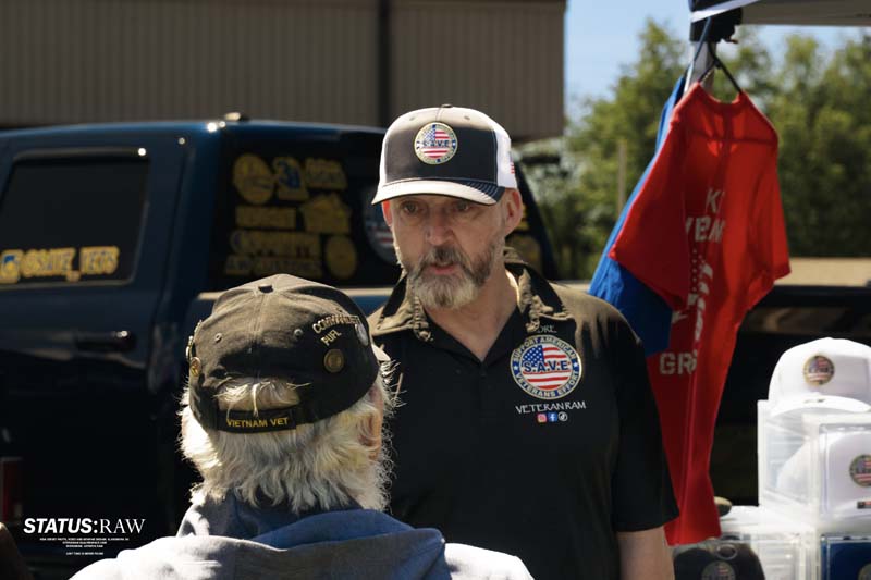Two people talking at outdoor event near veterans display