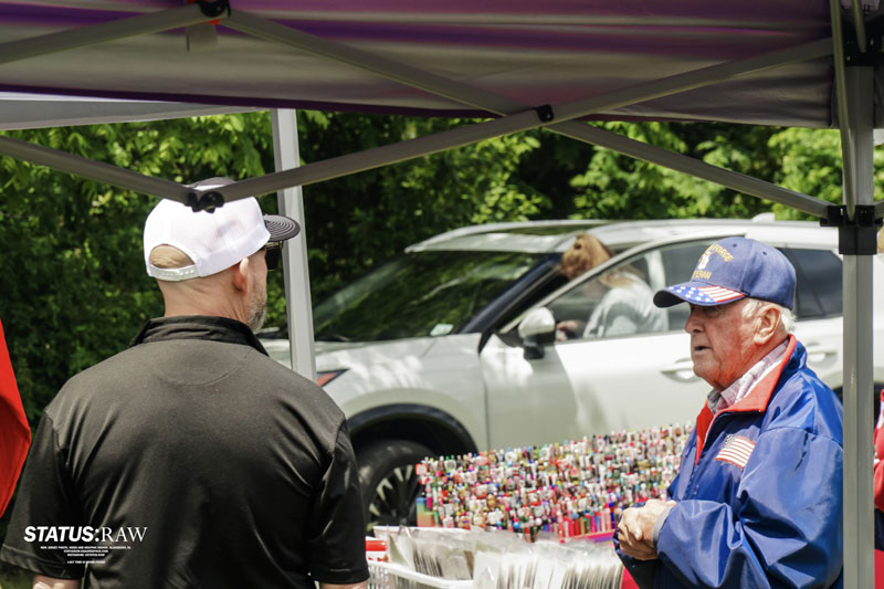 People talking at outdoor market stall under canopy